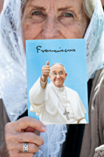 Femme agée tenant à la main une photo du pape François.