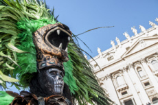 Homme au visage maquillé en tête de mort et portant une coiffe à tête d'animal.