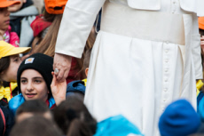 Un enfant tenant la main du pape François lors de l'audience générale.
