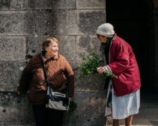 Deux paroissiennes discutent à la sortie de la messe des Rameaux.