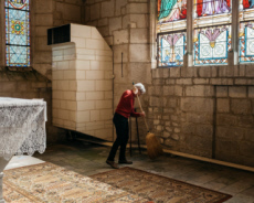 Femme dans l'Eglise. Membre de l'équipe paroissiale, balayant l'intérieur d'une église.