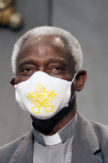 Le Card.TURKSON porte un masque de protection avec blason du Vatican.
