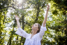 Jeune fille levant les bras, dans la nature.