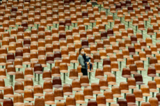 Une femme, son bébé dans les bras, marche au milieu de chaises vides.