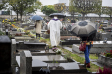 Fête de la Toussaint, prêtre et familles priant au cimetière.