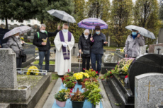 Fête de la Toussaint, prêtre et familles priant au cimetière.