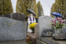 Fête de la Toussaint, prêtre et familles priant au cimetière.