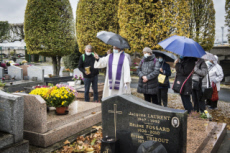 Fête de la Toussaint, prêtre et familles priant au cimetière.