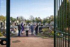 Fête de la Toussaint, prêtre et familles priant dans un cimetière.