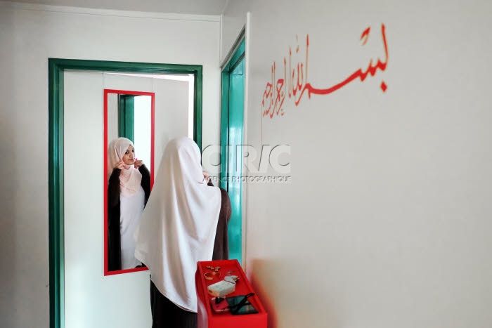 Jeune musulmane, chez elle, revêtant le hijab.