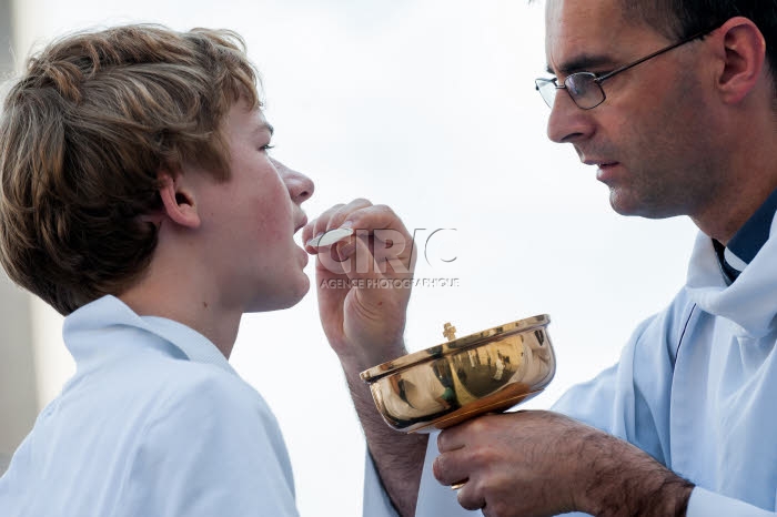 Un prêtre donnant la communion à un jeune garçon.