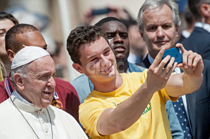 Le pape François fait un selfie aux côtés d'un jeune garçon.
