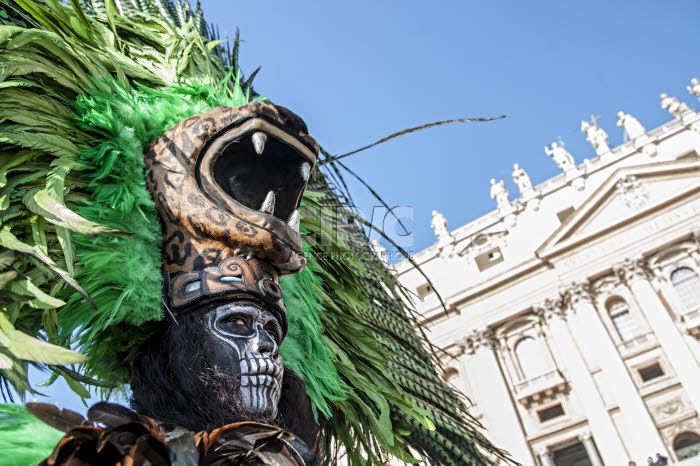 Homme au visage maquillé en tête de mort et portant une coiffe à tête d'animal.