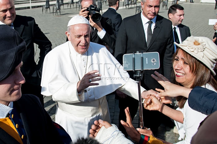Une femme fait une vidéo alors que le pape François vient la saluer.