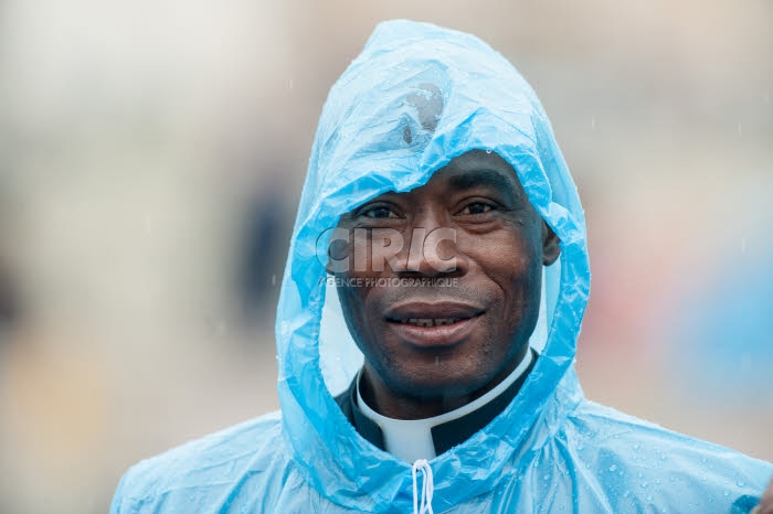 Prêtre avec imperméable bleu.