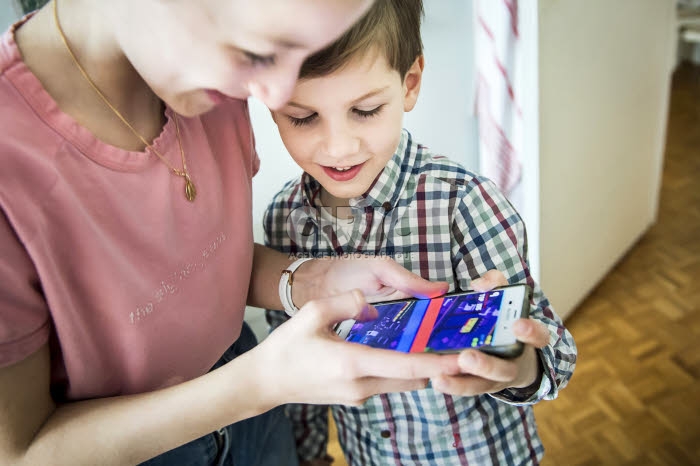 Garçon et fille jouant sur un téléphone portable.