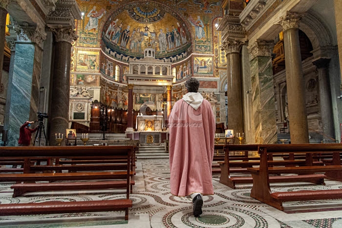 Prêtre arrivant dans une église vide où la messe sera filmée.