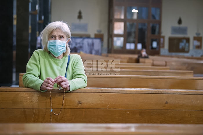 Coronavirus, fidèle, protégée par un masque, venue prier dans une église.