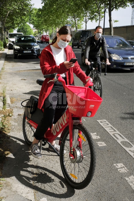 Coronavirus, déconfinement, jeune femme masquée et vélo électrique Uber.