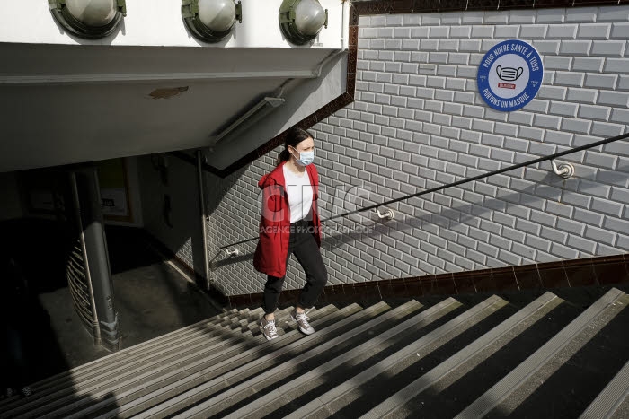 Coronavirus, jeune femme portant un masque de protection, sort du métro.