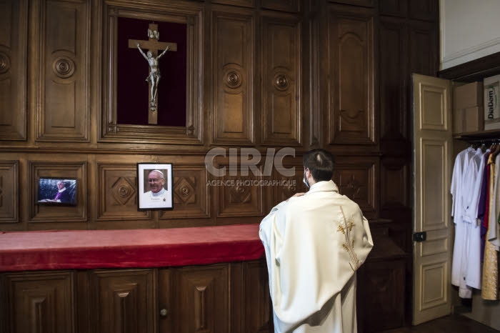 Prètre revêtant la chasuble dans la sacristie.