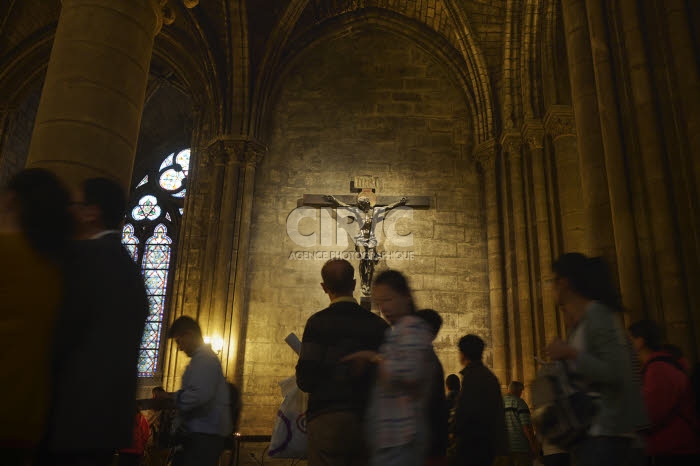 Christ en croix et touristes dans la cathédrale Notre-Dame à Paris