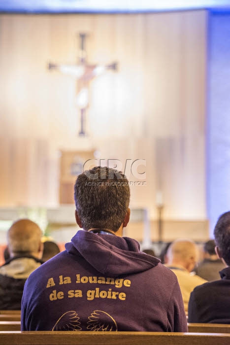 Prêtre portant un sweat-shirt sur lequel est écrit "A la louange de sa gloire".