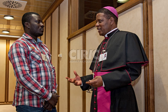Synode des évêques au Vatican. Evêque africain parlant avec un jeune homme.