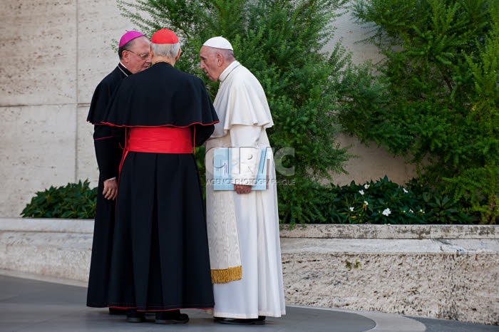 Synode des évêques. Le pape François converse avec un évêque et un cardinal.