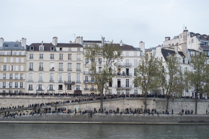 Personnes sur les quais de Seine regardant la cathédrale Notre-Dame en feu.