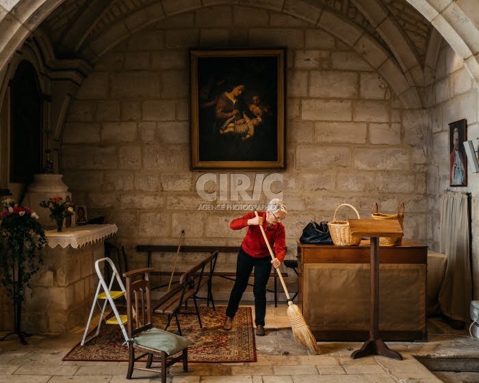 Femme dans l'Eglise. Membre de l'équipe paroissiale, balayant l'intérieur d'une église.
