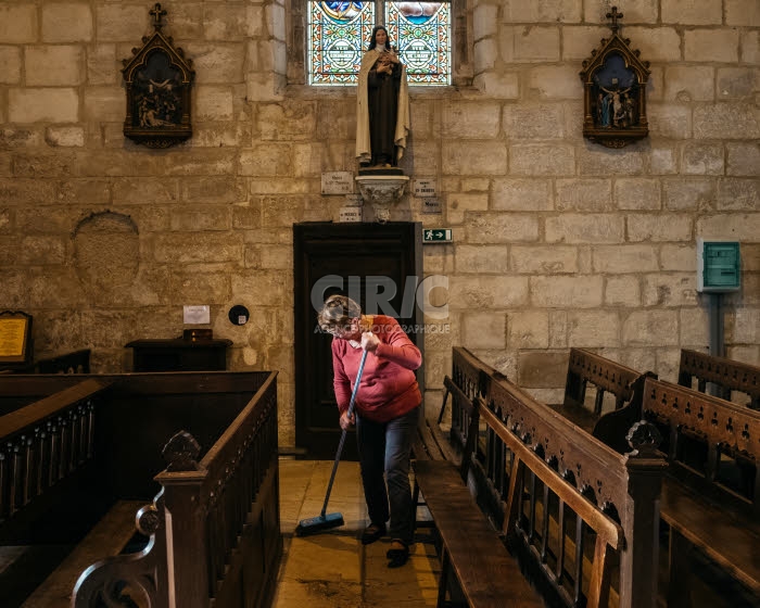 Femme dans l'Eglise. Membre de l'équipe paroissiale, balayant l'intérieur d'une église.