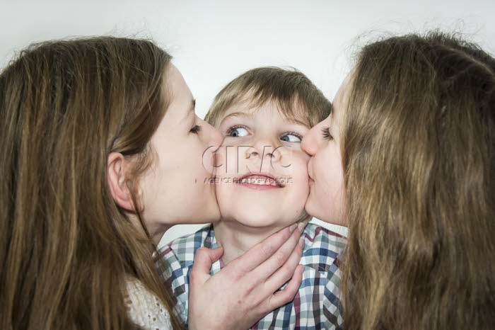 Des soeurs embrassent leur petit frère.