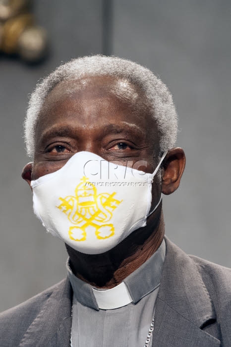 Le Card.TURKSON porte un masque de protection avec blason du Vatican.